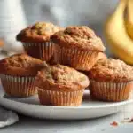 High protein banana muffins cooling on a marble counter in soft daylight