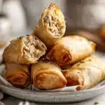 Cheesy tuna pie lumpia with golden crisp wrappers on a marble surface.