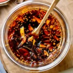 Homemade chili oil crunch in a glass jar with crispy garlic, shallots, and sesame seeds